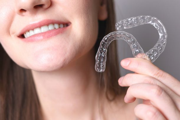 woman holding two Invisalign trays