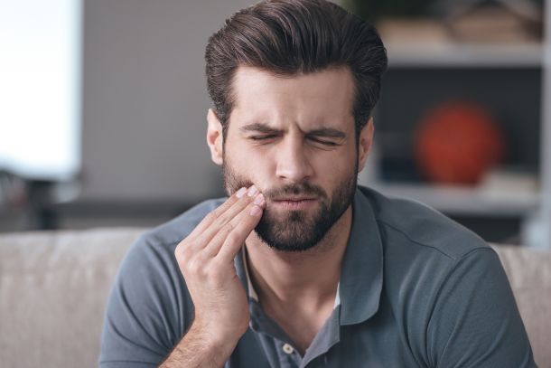 man touching his face because of braces pain