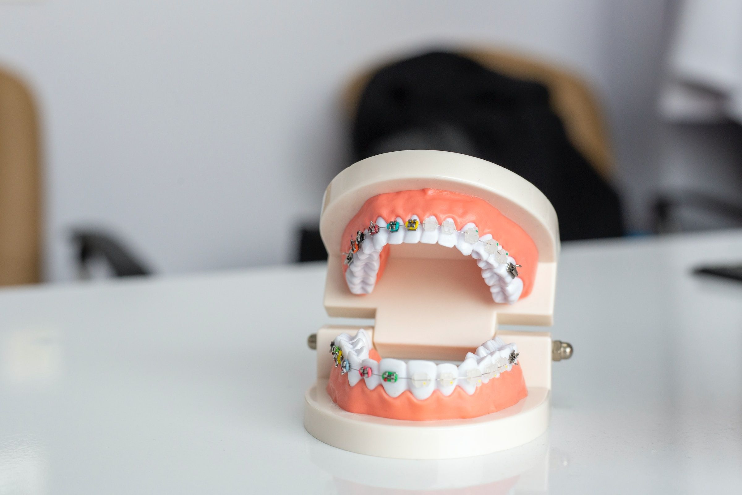 model of the mouth with clear braces and metal braces with colorful bands