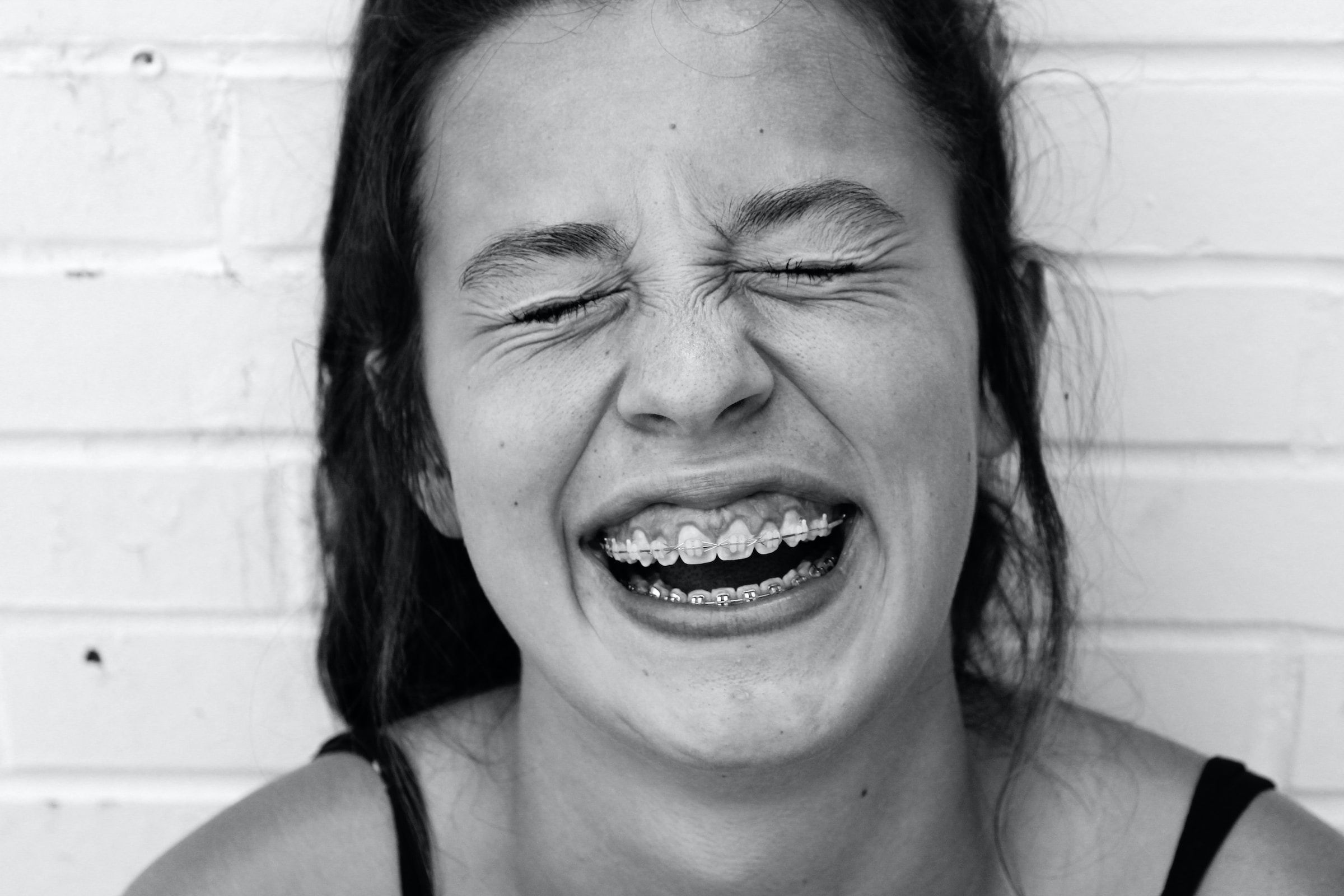black and white picture of teen laughing with braces