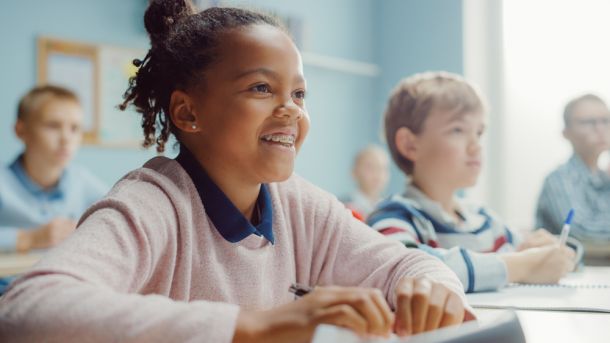 young black girl sitting in class, smiling, girl with braces