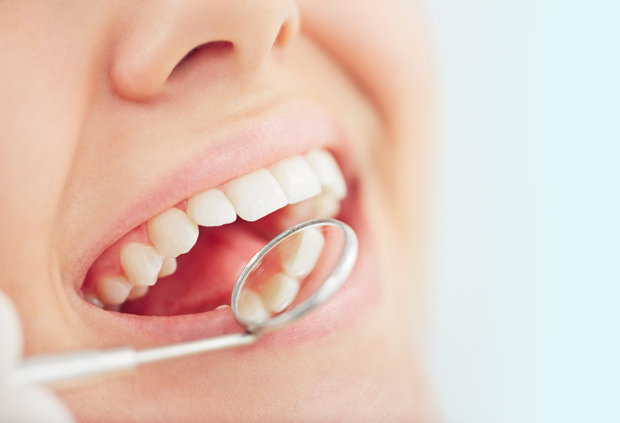close-up of woman getting teeth checked with a dental mirror